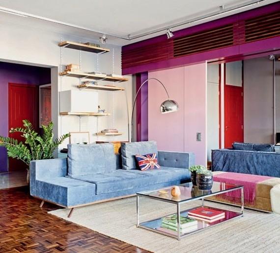 sala de estar com sofa cinza, tapete claro e acessorios modernos que contrastam com o piso de tacos de madeira