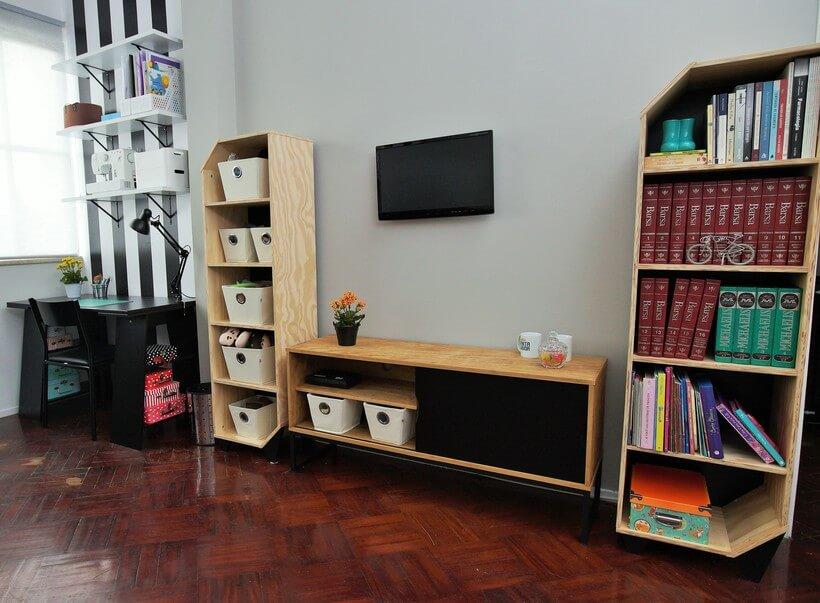 sala de tv com estantes altas para organizar livros e rack baixo no centro e tv acoplada na parede