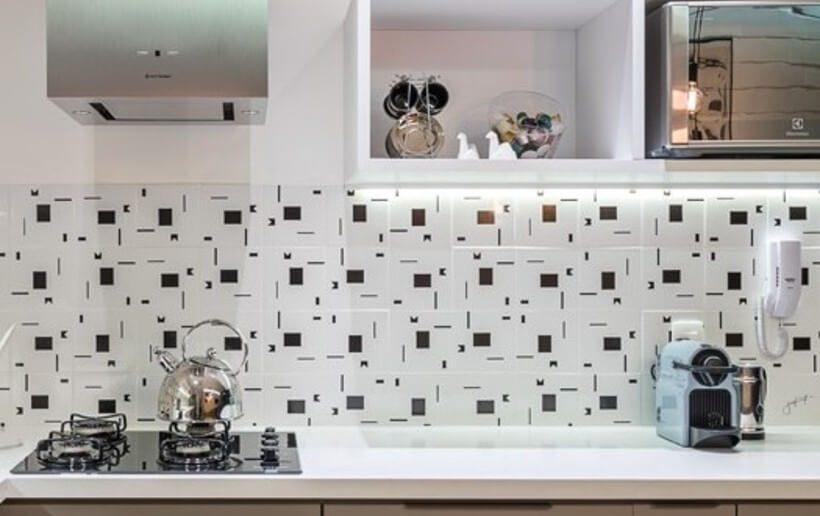 Detalhe da parede da pia de cozinha com revestimento em azulejo preto e branco geométrico