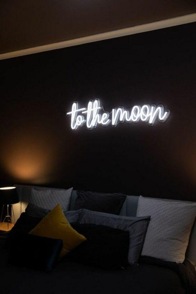 Letreiro neon em quarto escuro com a frase "to the moon": 
